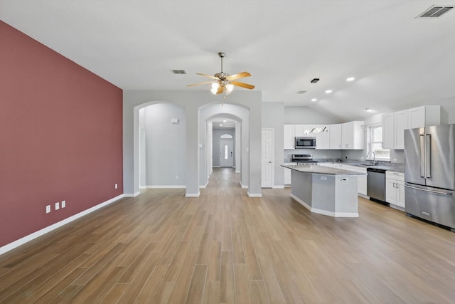 kitchen featuring stainless steel appliances, vaulted ceiling, visible vents, a kitchen island, and ceiling fan