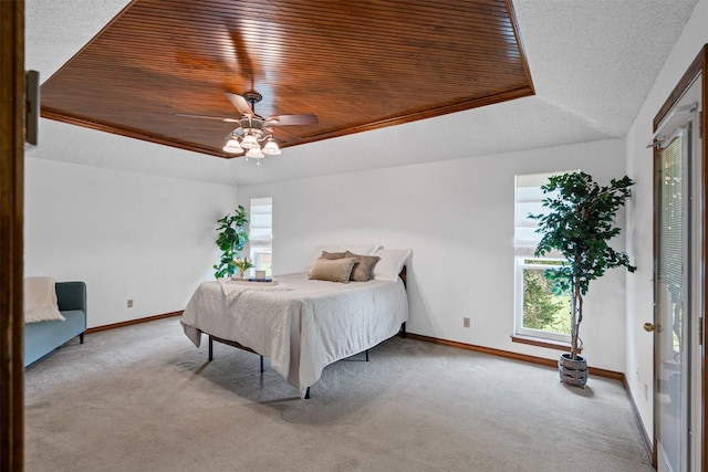 carpeted bedroom featuring baseboards, a tray ceiling, ceiling fan, and wood ceiling