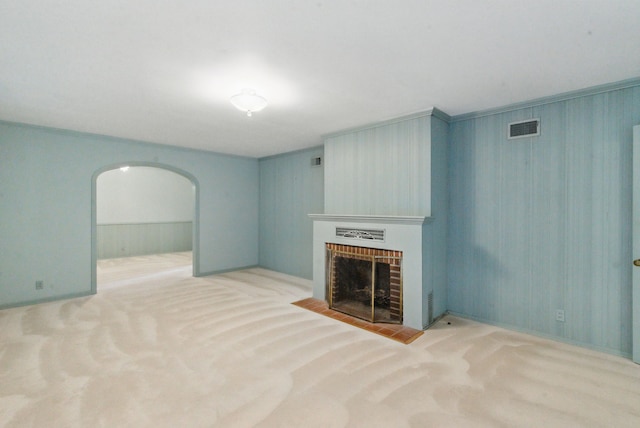 unfurnished living room with visible vents, arched walkways, carpet flooring, and a fireplace