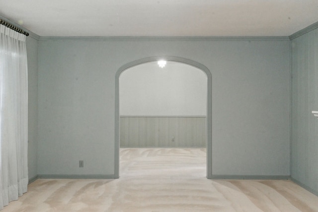 carpeted spare room featuring arched walkways and crown molding