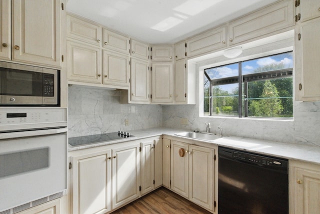 kitchen with black appliances, tasteful backsplash, a sink, and light countertops