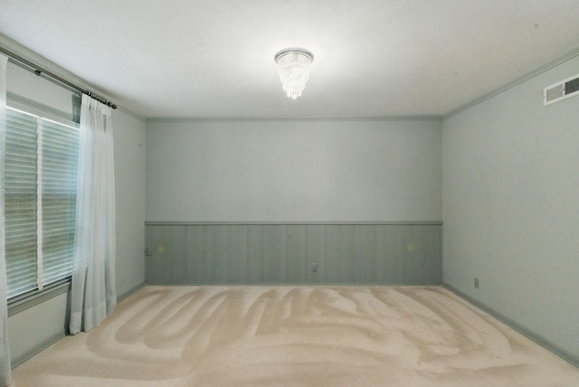 carpeted empty room featuring wainscoting and visible vents