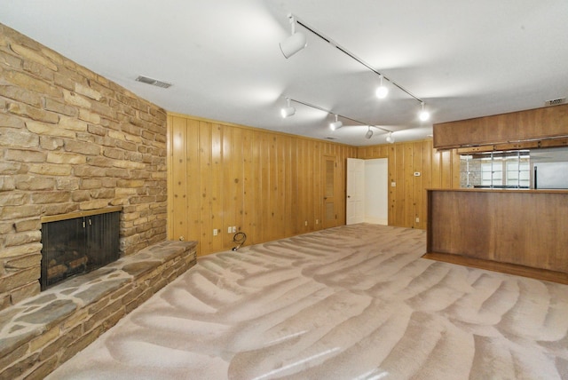 basement featuring wooden walls, a large fireplace, carpet flooring, visible vents, and freestanding refrigerator