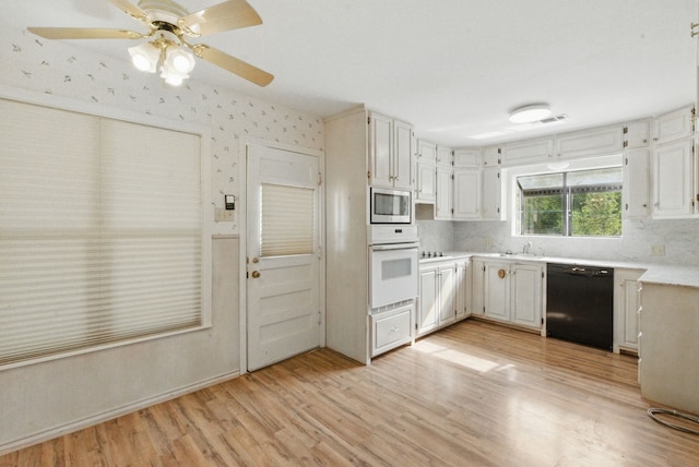kitchen with oven, light wood-style floors, dishwasher, light countertops, and stainless steel microwave