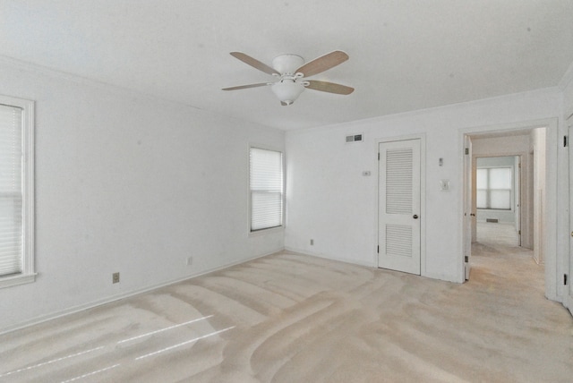 unfurnished room with ceiling fan, light carpet, ornamental molding, and visible vents
