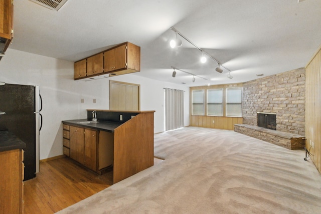kitchen with a sink, dark countertops, visible vents, freestanding refrigerator, and brown cabinets
