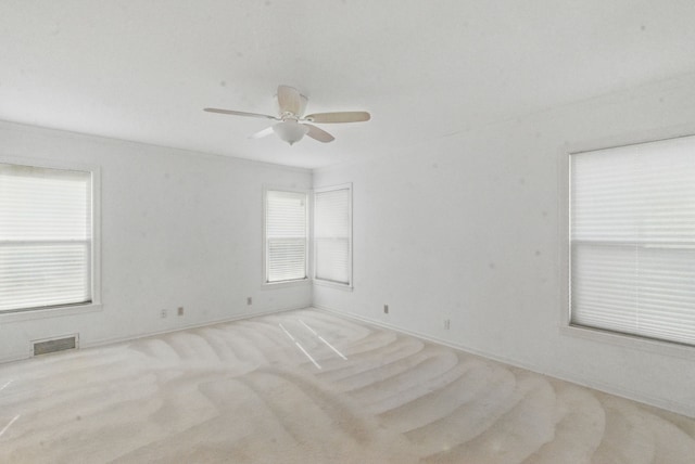 carpeted empty room featuring ceiling fan and visible vents