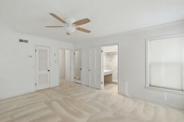 unfurnished bedroom with crown molding, ceiling fan, carpet, ensuite bath, and visible vents