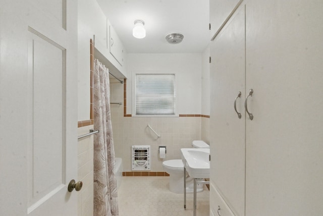 bathroom featuring heating unit, tile walls, a wainscoted wall, toilet, and a shower with shower curtain