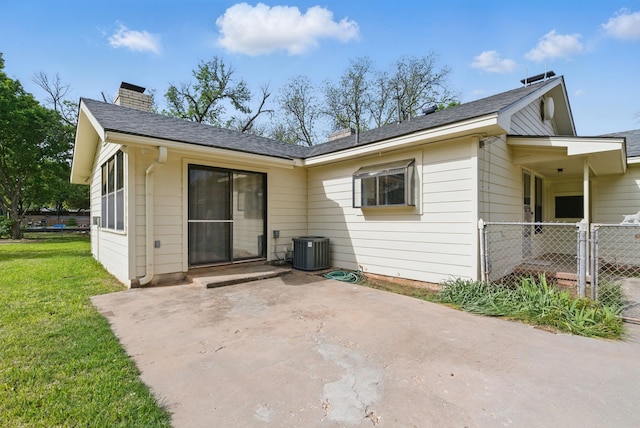 rear view of house with central air condition unit, a chimney, fence, a patio area, and a yard