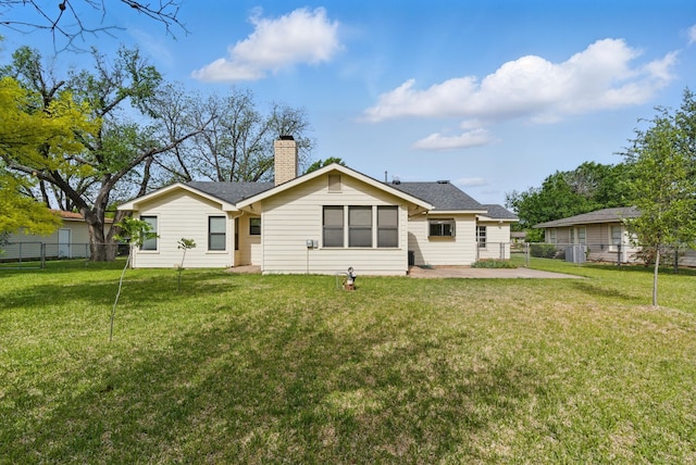 back of property featuring fence and a yard