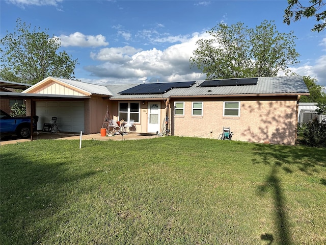 back of house with an attached garage, brick siding, a yard, and metal roof