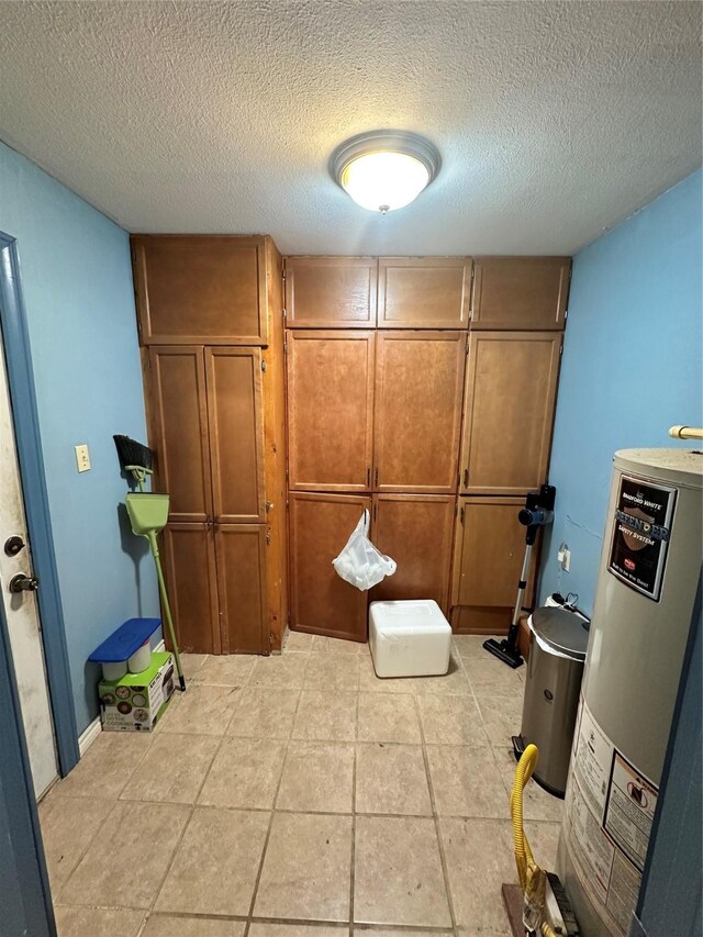 bathroom featuring water heater, tile patterned flooring, and a textured ceiling