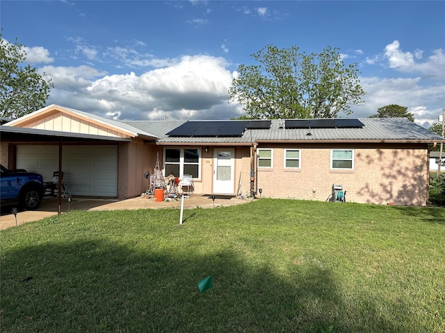 rear view of property with metal roof, brick siding, a yard, and a garage