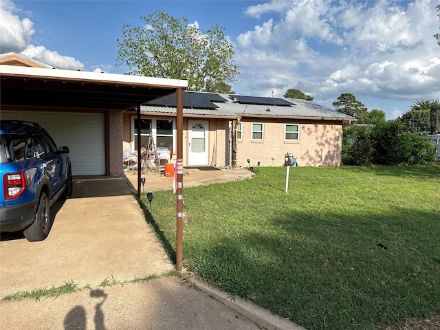 ranch-style house featuring roof mounted solar panels, concrete driveway, an attached garage, brick siding, and a front yard