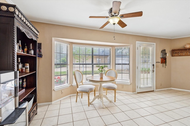 dining room with light tile patterned flooring, ornamental molding, baseboards, and ceiling fan