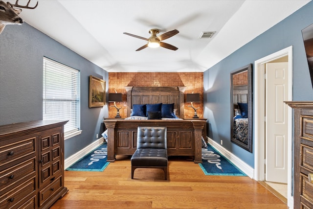 bedroom with baseboards, light wood-style flooring, visible vents, and a ceiling fan