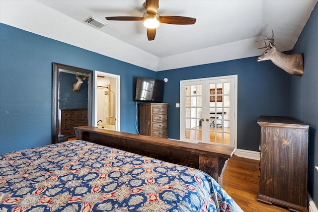 bedroom with a ceiling fan, wood finished floors, connected bathroom, lofted ceiling, and visible vents