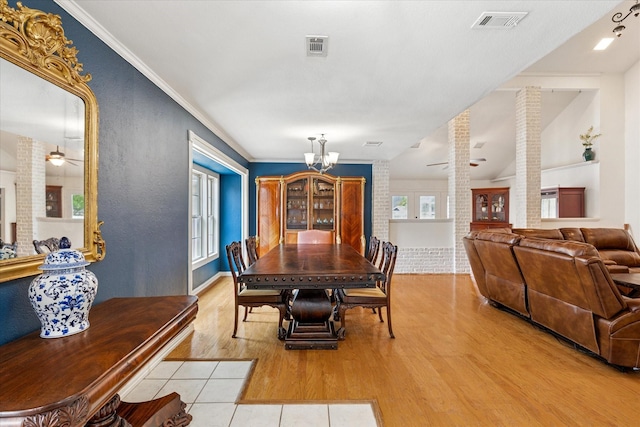 dining area featuring light wood-type flooring, decorative columns, visible vents, ceiling fan with notable chandelier, and crown molding