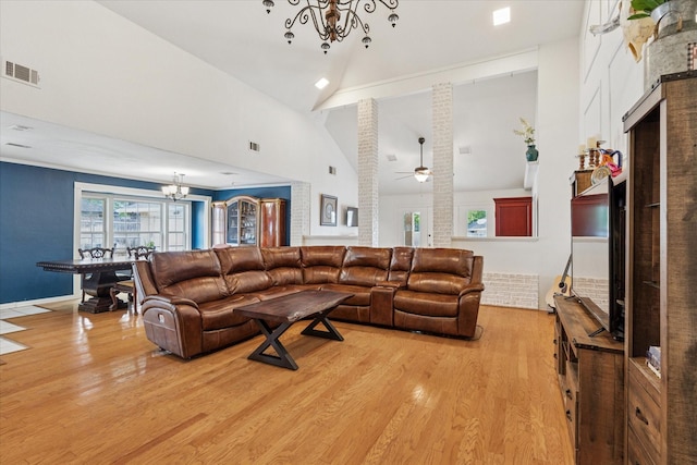 living room with visible vents, light wood finished floors, high vaulted ceiling, and ceiling fan with notable chandelier