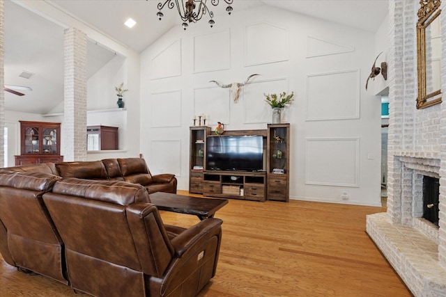 living area featuring high vaulted ceiling, light wood finished floors, and a fireplace