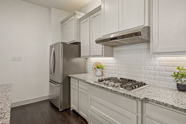 kitchen featuring under cabinet range hood, light stone countertops, decorative backsplash, appliances with stainless steel finishes, and dark wood-style flooring