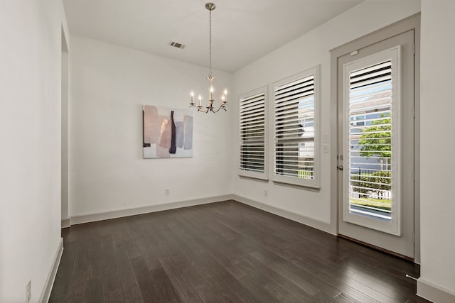 unfurnished dining area featuring dark wood-type flooring, visible vents, baseboards, and a notable chandelier