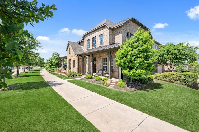 view of front of house with brick siding, a porch, a standing seam roof, and a front yard