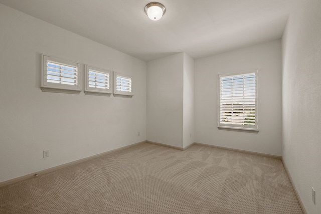 spare room with light carpet and baseboards