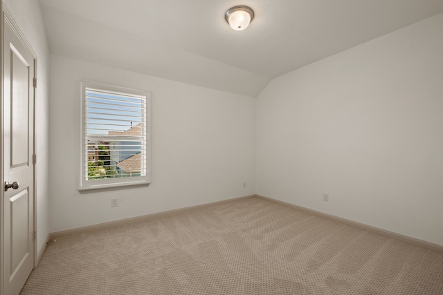 empty room with light colored carpet, baseboards, and lofted ceiling