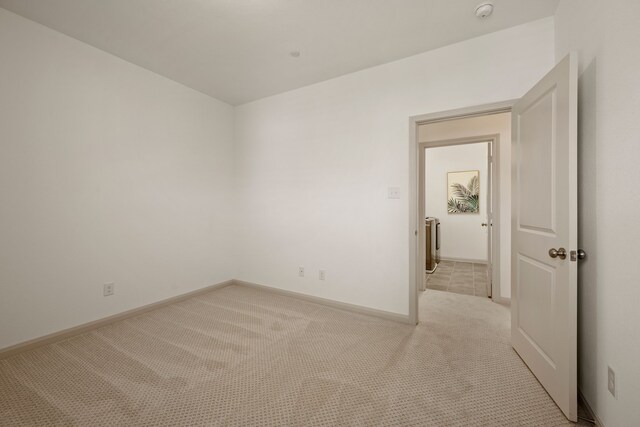 spare room with light carpet and baseboards