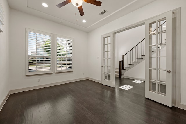 empty room featuring french doors, dark wood finished floors, visible vents, baseboards, and a ceiling fan