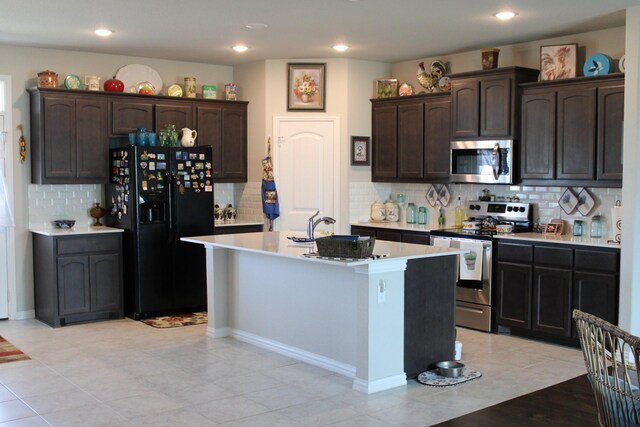 2267 County Road 4010, Decatur, TX 76234 - kitchen with stainless steel appliances, decorative backsplash, dark brown cabinetry, an island with sink, and light countertops