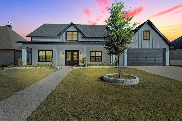 modern inspired farmhouse with a lawn, a standing seam roof, board and batten siding, and french doors