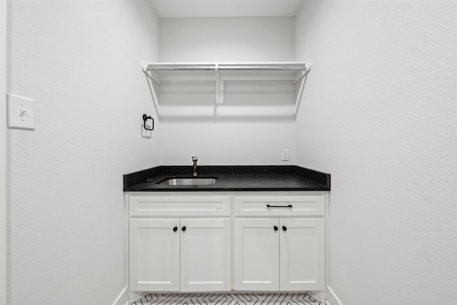 bar with indoor wet bar, baseboards, and a sink