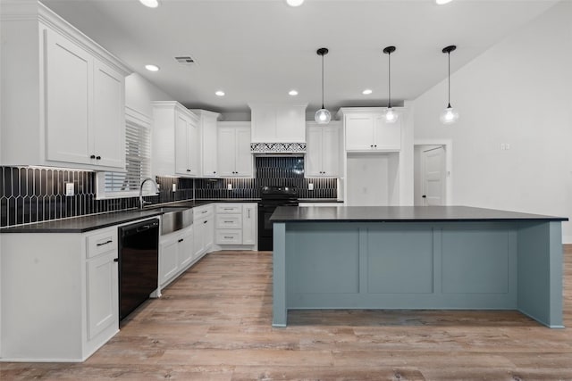 kitchen with black appliances, wall chimney exhaust hood, dark countertops, and a sink