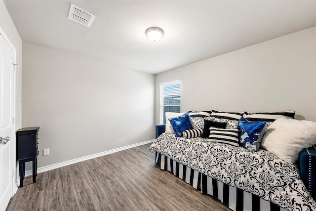 bedroom featuring baseboards, wood finished floors, and visible vents