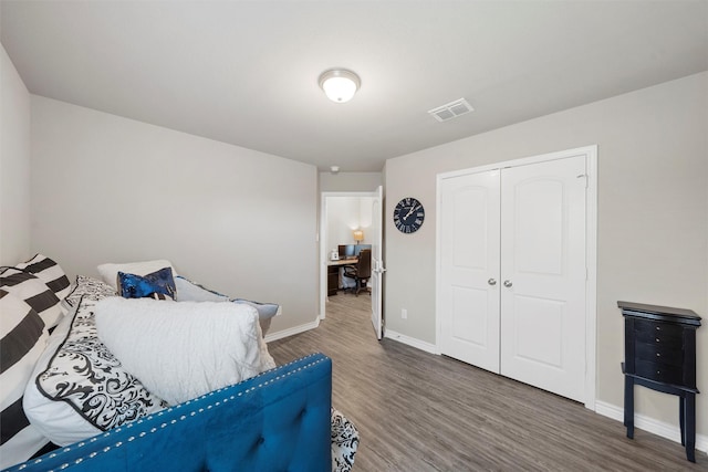 bedroom featuring a closet, wood finished floors, visible vents, and baseboards