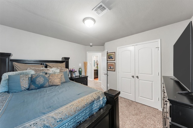 bedroom featuring light carpet, visible vents, a textured ceiling, and a closet