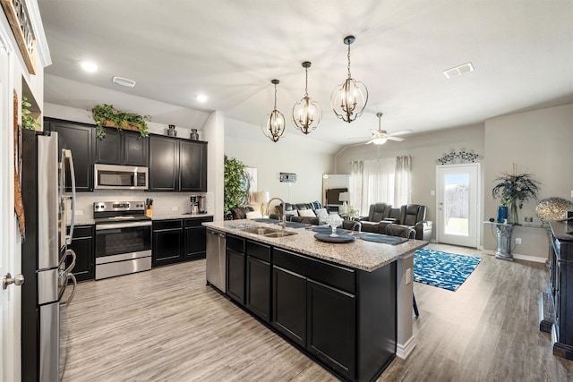 kitchen with stainless steel appliances, a sink, light wood-style floors, open floor plan, and ceiling fan with notable chandelier