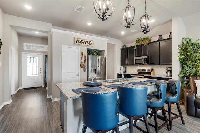 kitchen with tasteful backsplash, a sink, appliances with stainless steel finishes, a notable chandelier, and visible vents