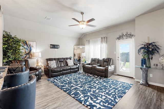 living area with vaulted ceiling, wood finished floors, visible vents, baseboards, and ceiling fan