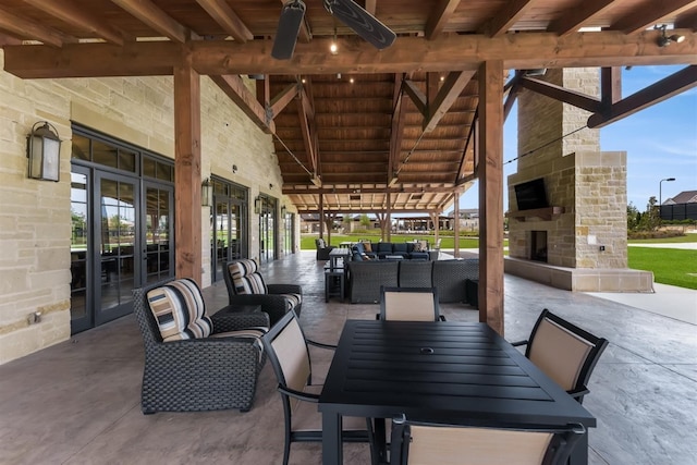view of patio featuring an outdoor living space with a fireplace, a ceiling fan, french doors, and outdoor dining space
