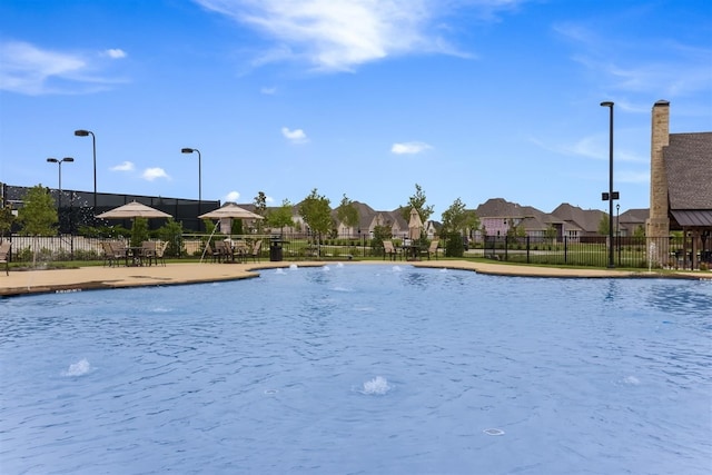 community pool with a residential view, a patio area, and fence
