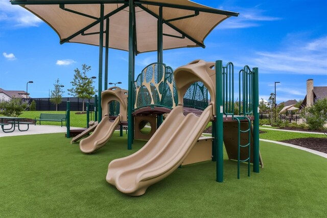 community play area featuring a yard and fence