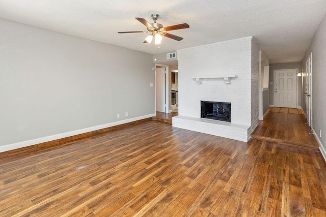 unfurnished living room with visible vents, baseboards, a ceiling fan, wood finished floors, and a fireplace