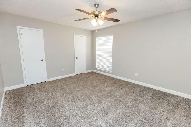 carpeted empty room featuring ceiling fan, baseboards, and a textured ceiling