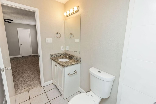 half bathroom with a textured ceiling, vanity, baseboards, toilet, and tile patterned flooring