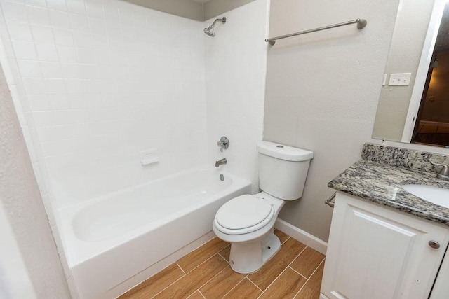 bathroom with toilet, vanity, baseboards,  shower combination, and wood finish floors
