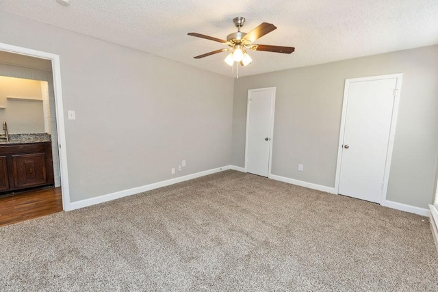 unfurnished bedroom with baseboards, carpet floors, a textured ceiling, and a sink
